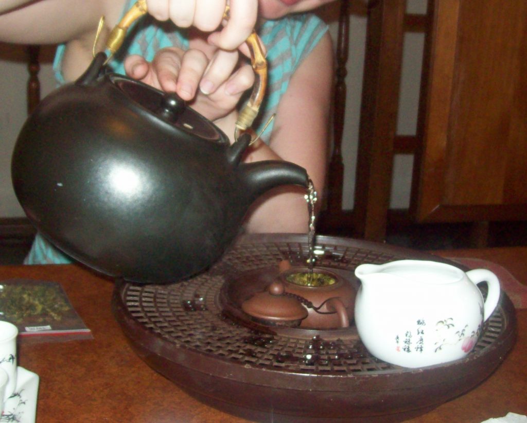Pouring water from the kettle into a pot of tea